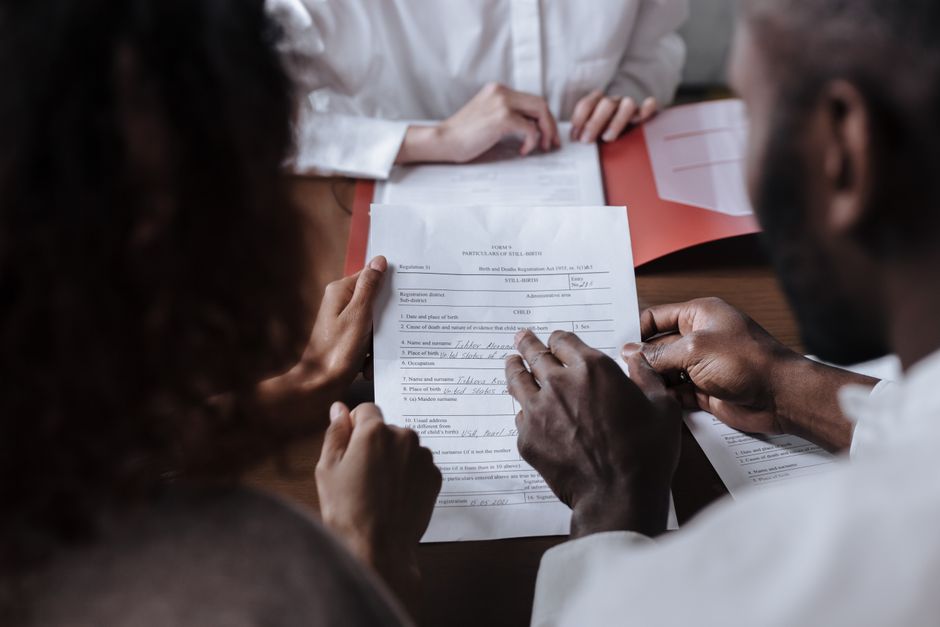 Couple signant un document officiel chez un notaire dans un bureau élégant.